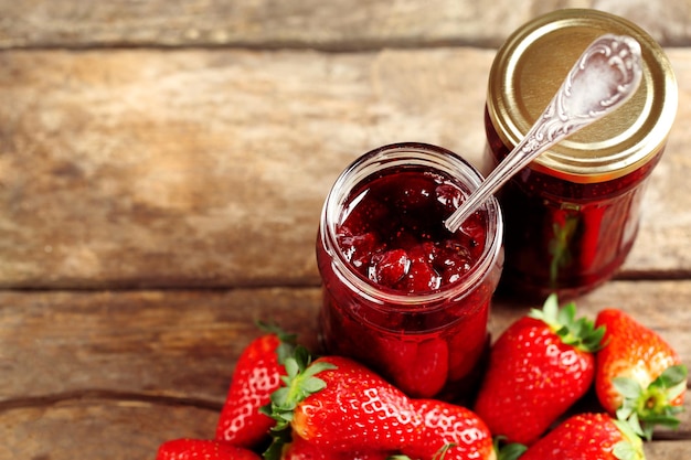 Pots de confiture de fraises aux fruits rouges sur fond de bois