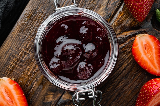 Pots de confiture de fraises aux fruits rouges, sur fond noir, vue de dessus à plat