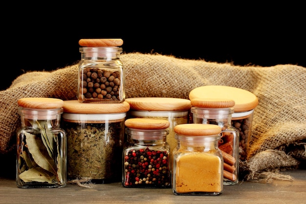 Pots d'épices sur table en bois sur fond noir