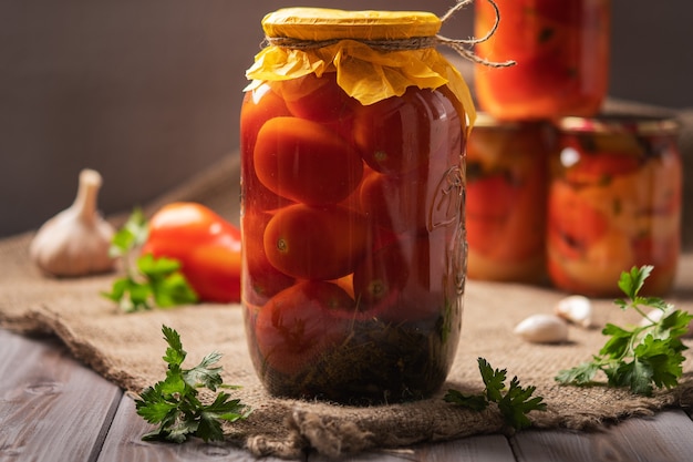 Pots faits maison de tomates marinées sur un fond en bois rustique produit mariné et en conserve à côté