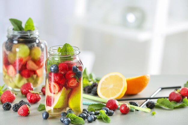 Pots Mason d'eau infusée avec des fruits et des baies sur la table