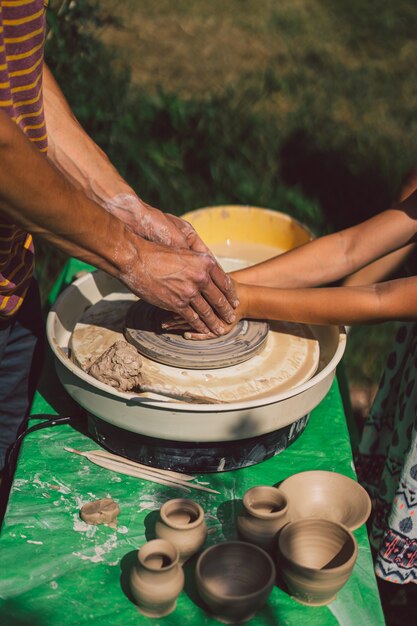 Potter faisant un objet en argile sur un tour de potier en plein air artisan mouler l'argile avec les mains sur la potte...