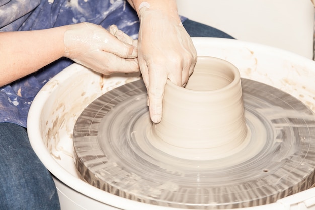 Potter femelle créant un pot en terre sur la roue d'un potier