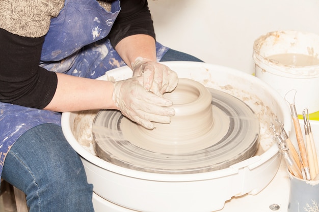 Potter femelle créant un pot en terre sur la roue d'un potier