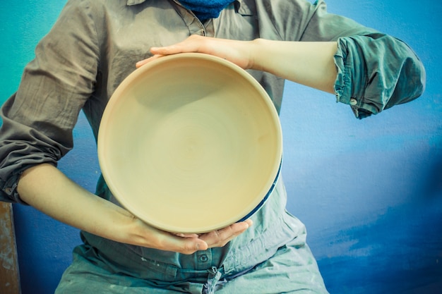 Potter tient une plaque d'argile ronde dans ses mains