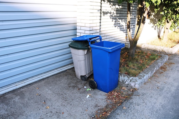 Photo poubelle près de la clôture en pierre dans la rue conteneur pour ordures et déchets dans la zone suburbaine