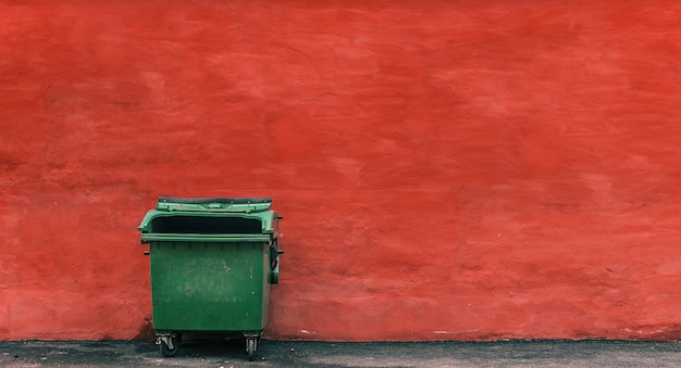 Photo poubelle verte sur fond de mur rouge