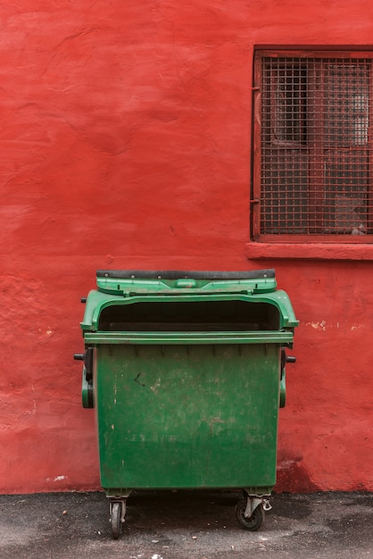 Poubelle verte sur fond de mur rouge