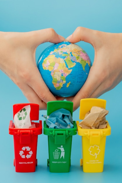 Poubelles de recyclage jaunes, vertes et rouges avec symbole de recyclage sur fond bleu.