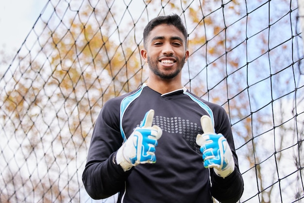 Pouce en l'air gardien de but et portrait d'homme sur le terrain de football pour le gagnant du succès et la réalisation Entraînement sportif et compétition avec gardien de but masculin sur le terrain de football pour la défense et le jeu de la compétition