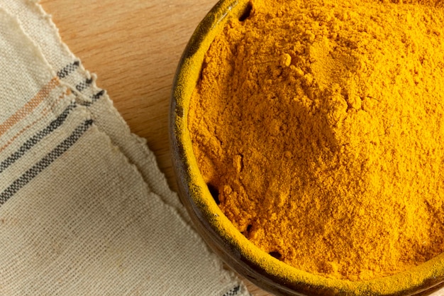 Poudre de curcuma dans un bol en bois