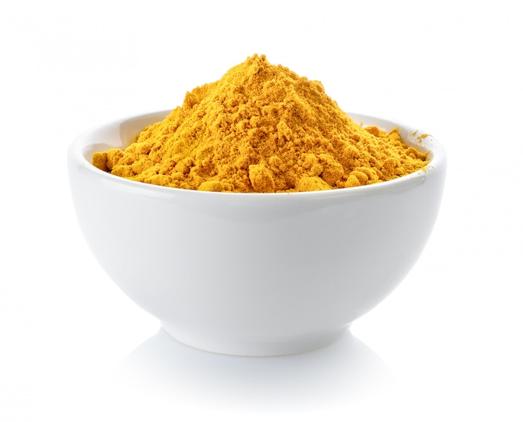 Photo poudre de curcuma dans un bol sur un espace blanc