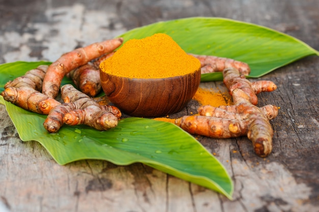 Poudre de curcuma dans des bols en bois sur une table en bois