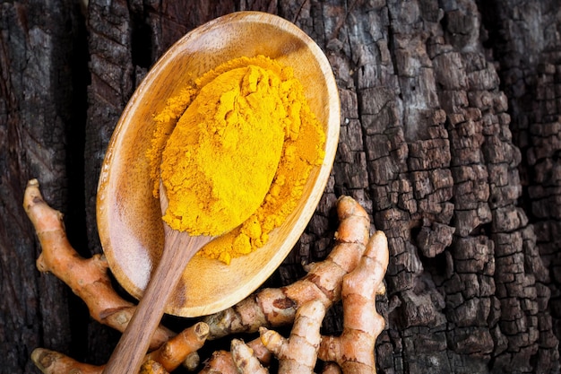 Photo poudre de curcuma dans une cuillère en bois sur une vieille table en bois à base de plantes