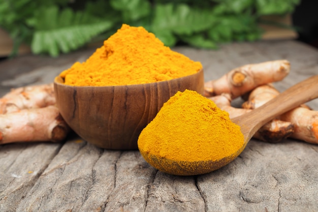 Poudre de curcuma dans une cuillère en bois sur une vieille table en bois. Les herbes sont originaires d'Asie du Sud-Est.