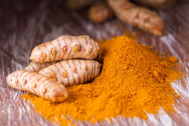 Poudre de curcuma et racines sur fond en bois