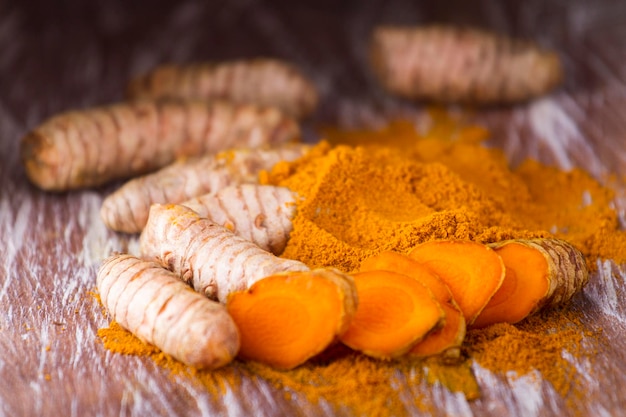 Poudre de curcuma et racines sur fond en bois