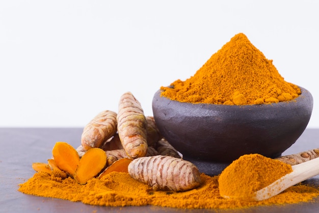 Poudre de curcuma et racines sur fond en bois