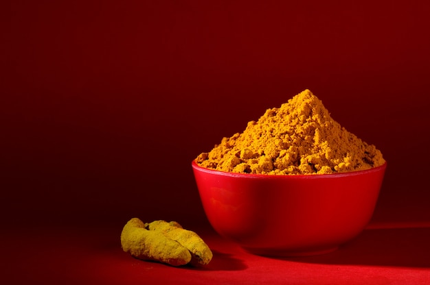 Poudre de curcuma sec dans un bol rouge