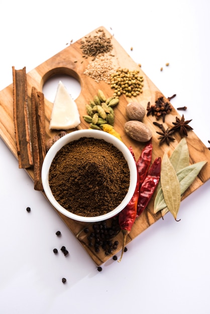 Poudre indienne de garam masala dans un bol et ses ingrédients d'épices colorées. Servi sur fond de mauvaise humeur. mise au point sélective