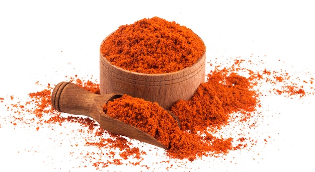 Poudre de paprika rouge dans un bol en bois et une cuillère isolé sur blanc