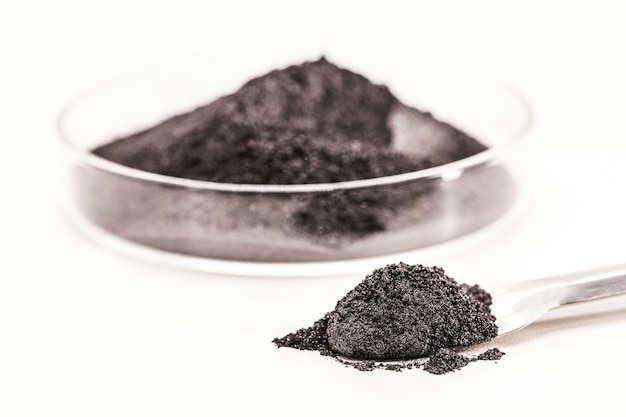 Poudre de pigment noir à usage industriel ou cosmétique fond blanc isolé dans une boîte de Pétri