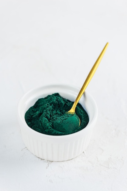 Poudre de spiruline dans une cuillère et un bol