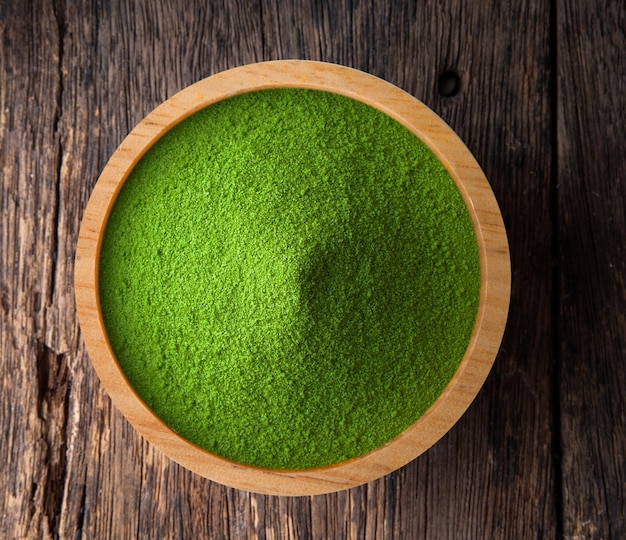 Poudre de thé vert dans un bol sur bois