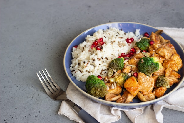 Poulet au curry avec du riz, des champignons et du brocoli décoré de graines de grenade