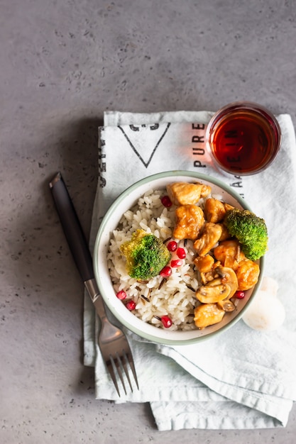 Poulet au curry avec du riz, des champignons et du brocoli décoré de graines de grenade