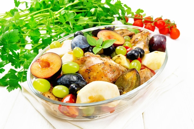 Poulet aux fruits et tomates dans une poêle sur planche de bois clair