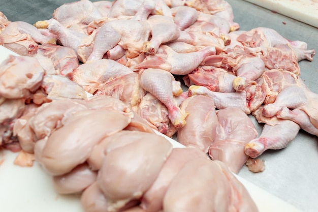 Poulet cru sur un comptoir avec l'une des cuisses de poulet à droite.