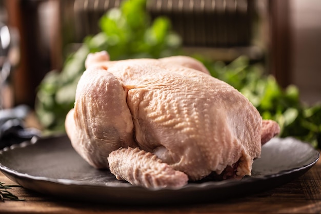 Poulet cru entier sur assiette dans la cuisine prêt à griller.