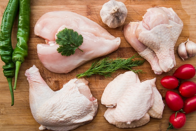 Photo poulet cru et ingrédients pour cuisiner sur une table en bois