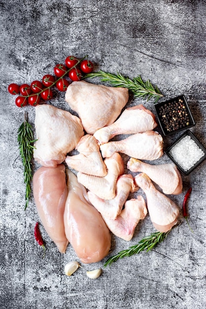 Poulet cru sur une table avec des épices et des herbes