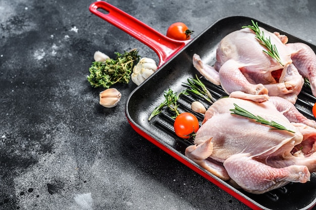 Poulet entier cru de ferme biologique dans une casserole. Fond noir. Vue de dessus. Copiez l'espace.