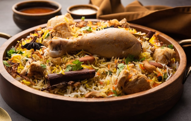 Poulet épicé Biryani de style restaurant servi avec Raita et Salan, nourriture non végétarienne populaire indienne ou pakistanaise