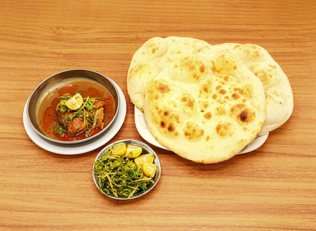 Poulet épicé korma khamiri roti tranche de citron et salade servis dans un plat isolé sur une table en bois vue latérale de la nourriture pakistanaise indienne