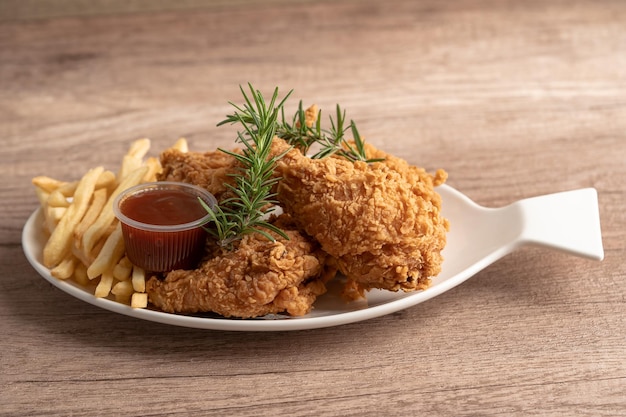 Poulet frit et chips de pomme de terre avec feuille de romarin, malbouffe riche en calories servie sur plaque blanche