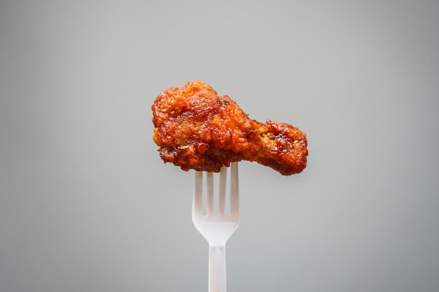 Poulet frit à la coréenne sur une fourchette en plastique avec fond gris