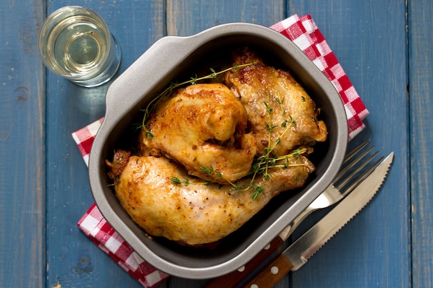 Poulet frit dans un plat sur une table brune et un verre de vin blanc