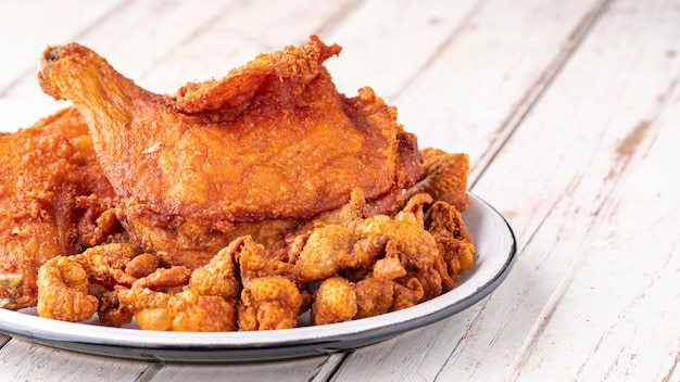 Poulet frit et peau de poulet frit dans une assiette en céramique sur fond de texture de bois ancien blanc avec espace de copie pour le texte