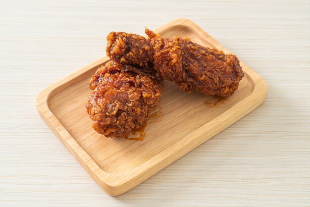 poulet frit avec sauce coréenne épicée sur plaque de bois