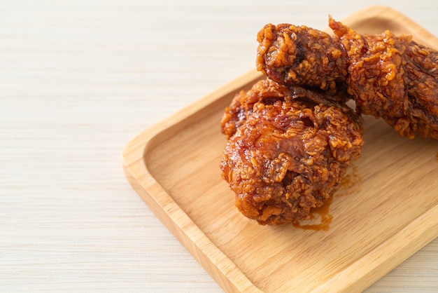 poulet frit avec sauce coréenne épicée sur plaque de bois