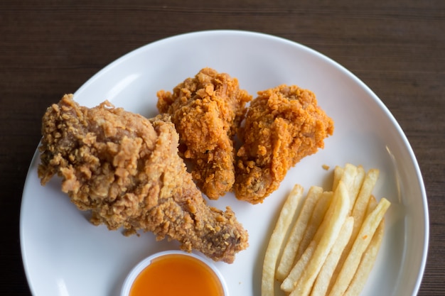 Photo poulet frit et sauce sur une plaque blanche faible lumière ou sous-exposée