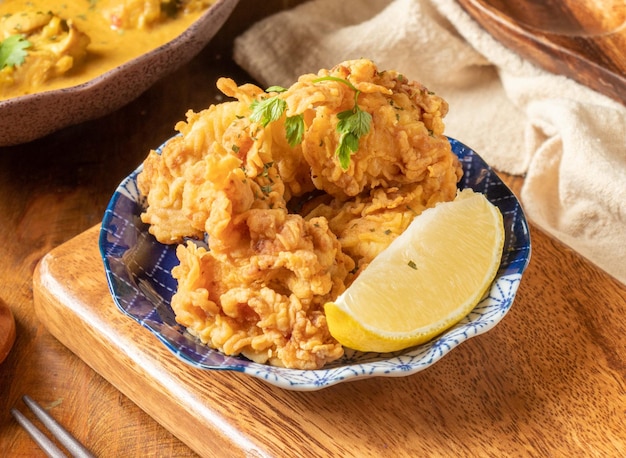 Poulet frit yuan coréen au citron vert dans une assiette noire sur une assiette en bois vue de dessus de la cuisine chinoise