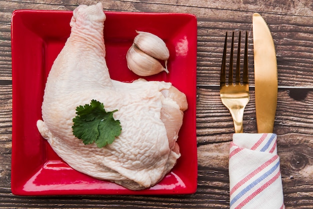 Poulet garni dans l&#39;assiette avec une fourchette et un couteau à beurre sur une table en bois