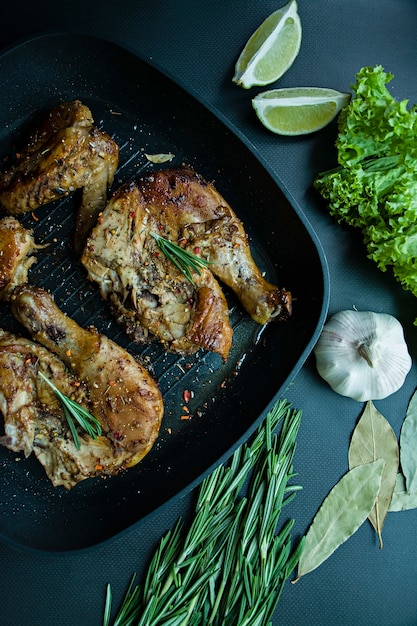 Poulet grillé dans une lèchefrite de légumes sur un fond sombre.