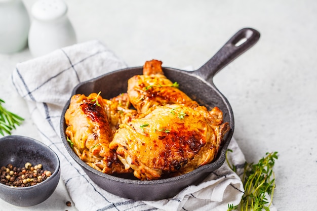 Poulet grillé dans une poêle en fonte, fond blanc.