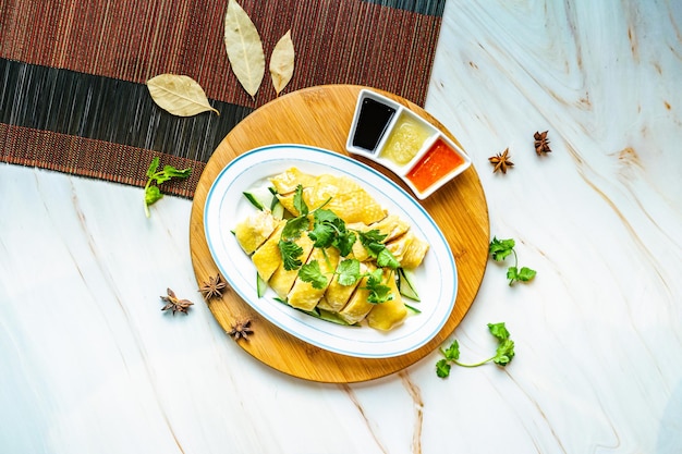 Poulet hainanais avec sauces servi dans un plat isolé sur une planche de bois vue de dessus sur fond de marbre nourriture de hong kong